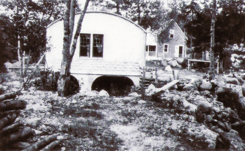 Une photo en noir et blanc montrant le toit arrondi de la centrale électrique sur la East River et la rivière s’écoulant sous la centrale. A droite de la centrale, on peut voir une petite maison où habitait avec sa famille l’opérateur de la centrale.