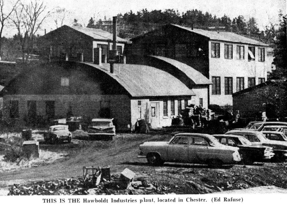 Une photo en noir et blanc de l’entreprise montrant le bureau sur la rue North. A l’arrière-plan se trouvent l’atelier de fabrication de deux étages ainsi que, à gauche de l’atelier, les bâtiments pour la fonte et le soudage au toit arrondi. Le parking des employés est au premier plan à côté du ruisseau.