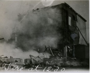 Photographie en noir et blanc d’un édifice en feu.