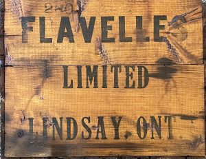 Caisse de bois imprimée des mots Flavelles Limited Lindsay, ONT, en caractères gras noirs.