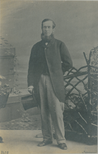 Photographie de studio d’un homme debout avec son chapeau haut-de-forme en main. 