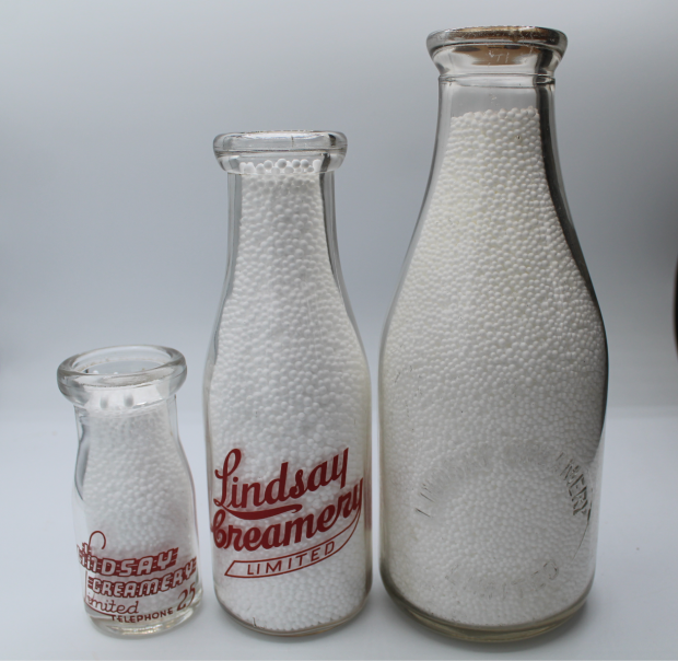 Trois différents formats de bouteilles de lait qui sont estampées ou affixées d’une étiquette de couleur