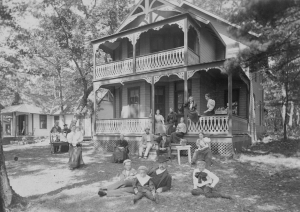 Des adultes et enfants à l’extérieur d’un chalet de deux étages.