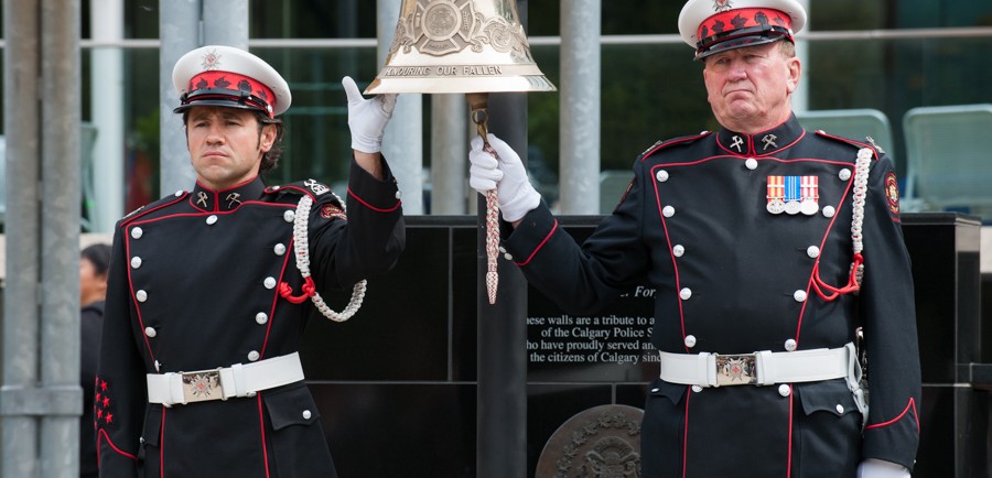 Deux membres de la garde d’honneur en uniforme de grande tenue avec gants blancs s’occupent de faire sonner et de tenir la grosse cloche suspendue à la place de l’hommage (Tribute Plaza), hôtel de ville. 