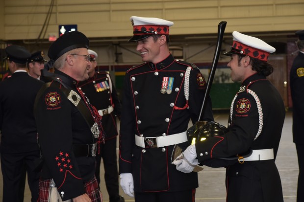 Deux membres de la Garde d'honneur et un cornemuseur de Pipes and Drums, tous en uniforme complet, rient en parlant ensemble