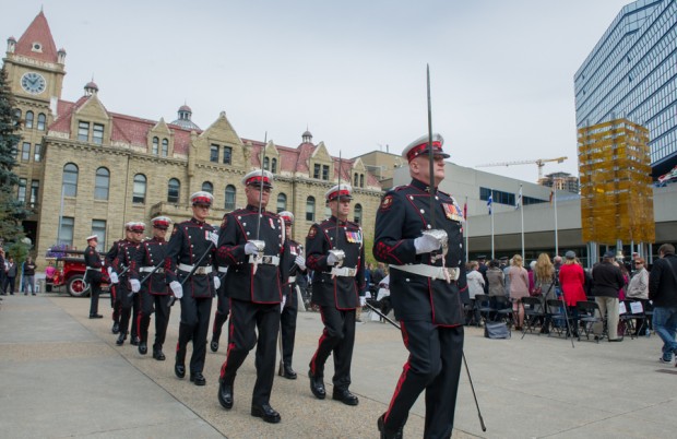 La garde d’honneur marche en uniforme de grande tenue en direction de la place de l’hommage (Tribute Plaza), en face de l’ancien hôtel de ville, épées et haches cérémoniales en main.