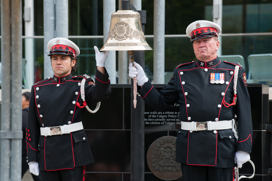 Deux membres de la garde d’honneur en uniforme de grande tenue avec gants blancs s’occupent de faire sonner et de tenir la grosse cloche suspendue à la place de l’hommage (Tribute Plaza), hôtel de ville. 