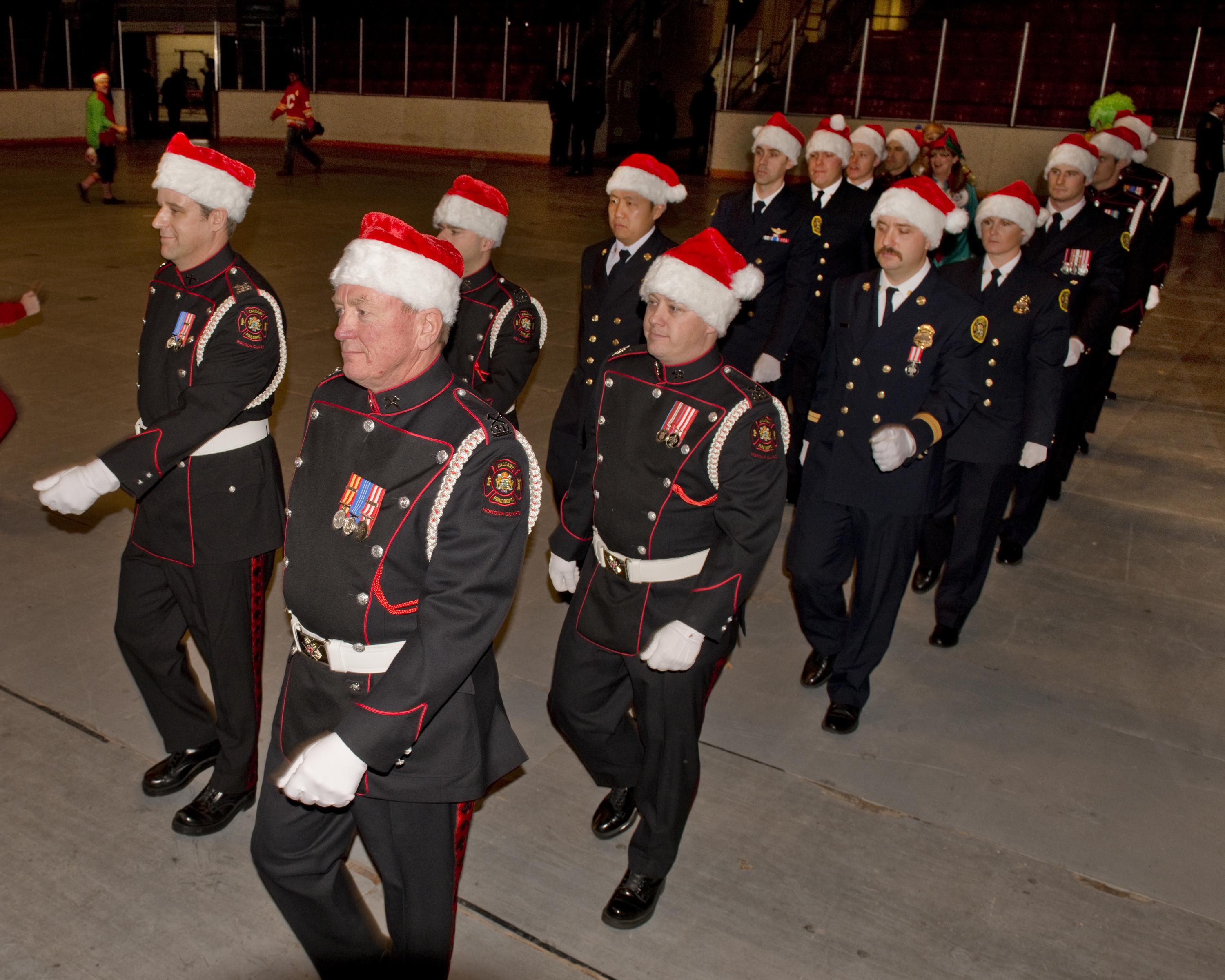 Deux rangs de pompiers en uniforme avec chapeau rouge de père Noël