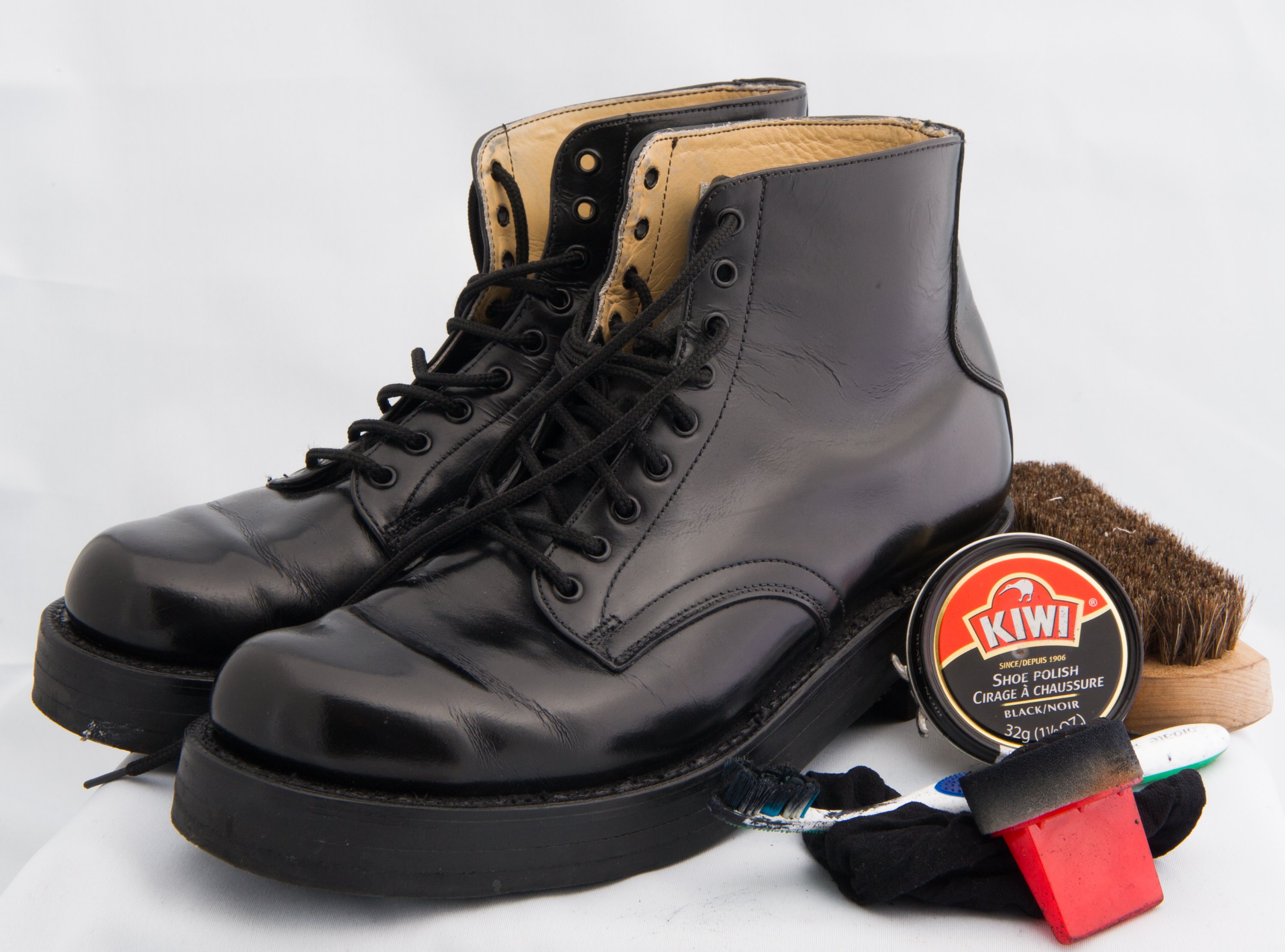 Bottes noires lacées de la garde d’honneur avec cire de marque Kiwi dans un contenant rond et brosse rouge