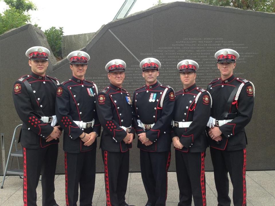 Six membres de la garde d’honneur les mains jointes, devant le monument commémoratif, à Ottawa