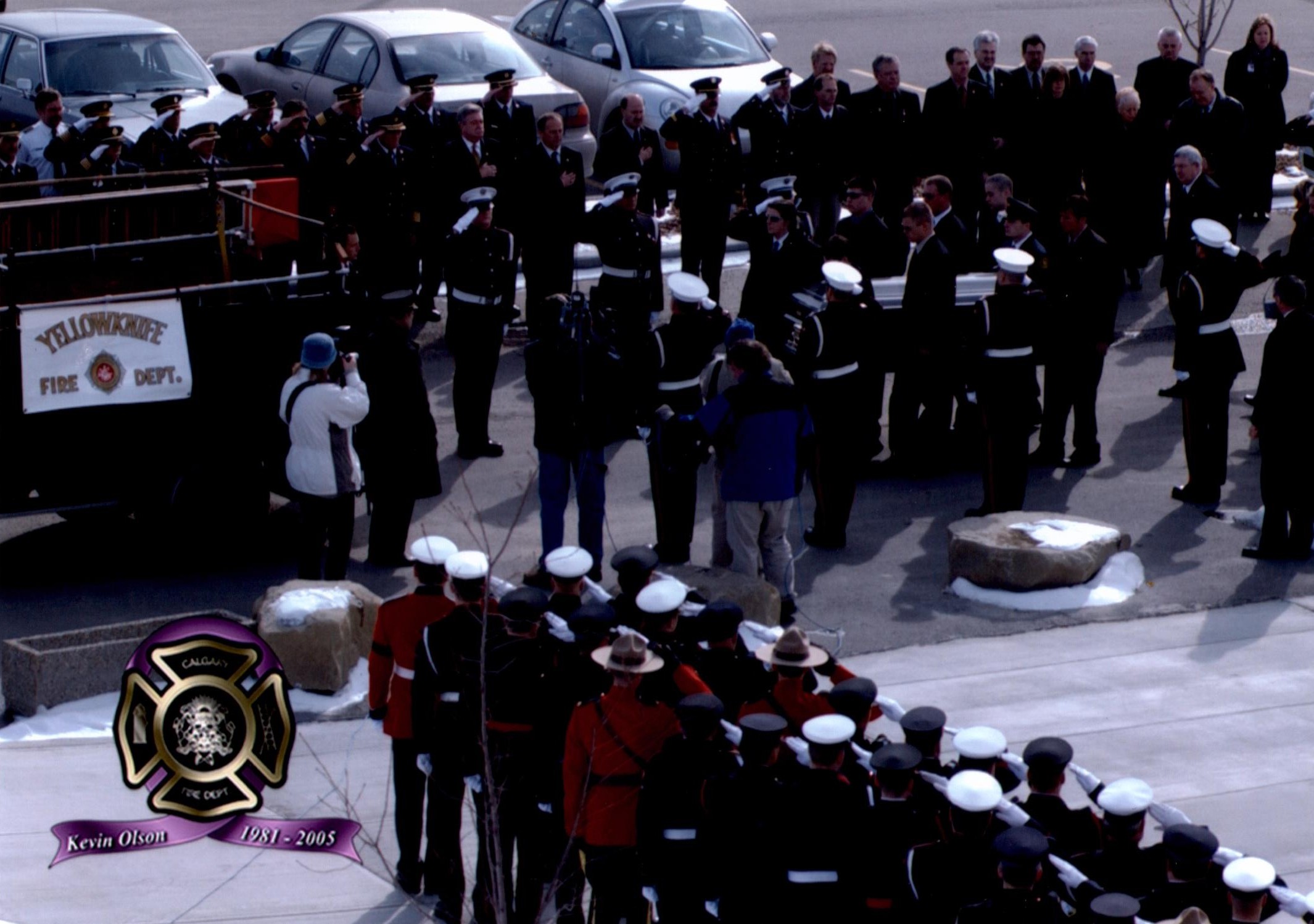 Des membres de la garde d’honneur embarquent le cercueil de Kevin Olson, pompier de Yellowknife, sur l’autopompe cérémoniale. Des pompiers et des polices montées sont au garde-à-vous et gardent le salut.