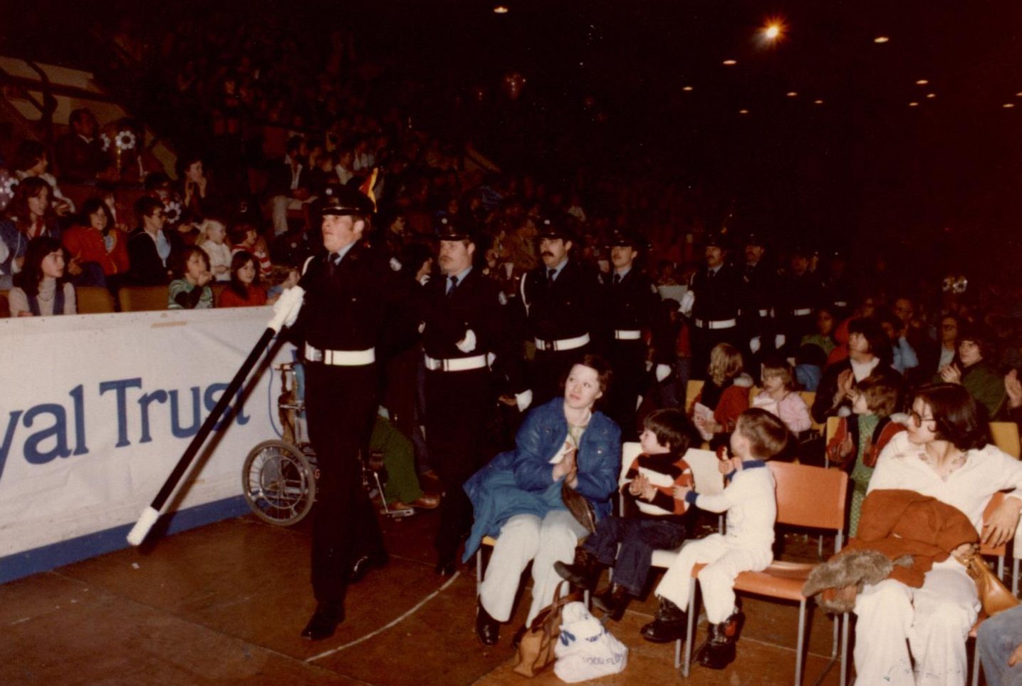 La garde d’honneur défile devant la foule assise dans les estrades et sur le plancher à l’occasion d’un défilé communautaire.