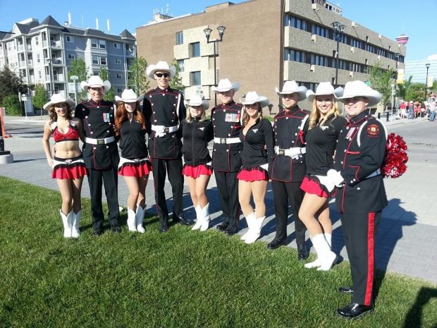 Cinq membres en uniforme de la garde d’honneur en compagnie de cinq Outriders des Stampeders, vêtues de leur costume de meneuses de claques et d’un chapeau blanc