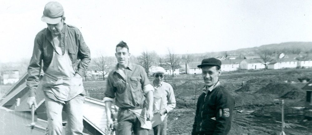 Photo noir et blanc d’un groupe de quatre hommes sur un toit.