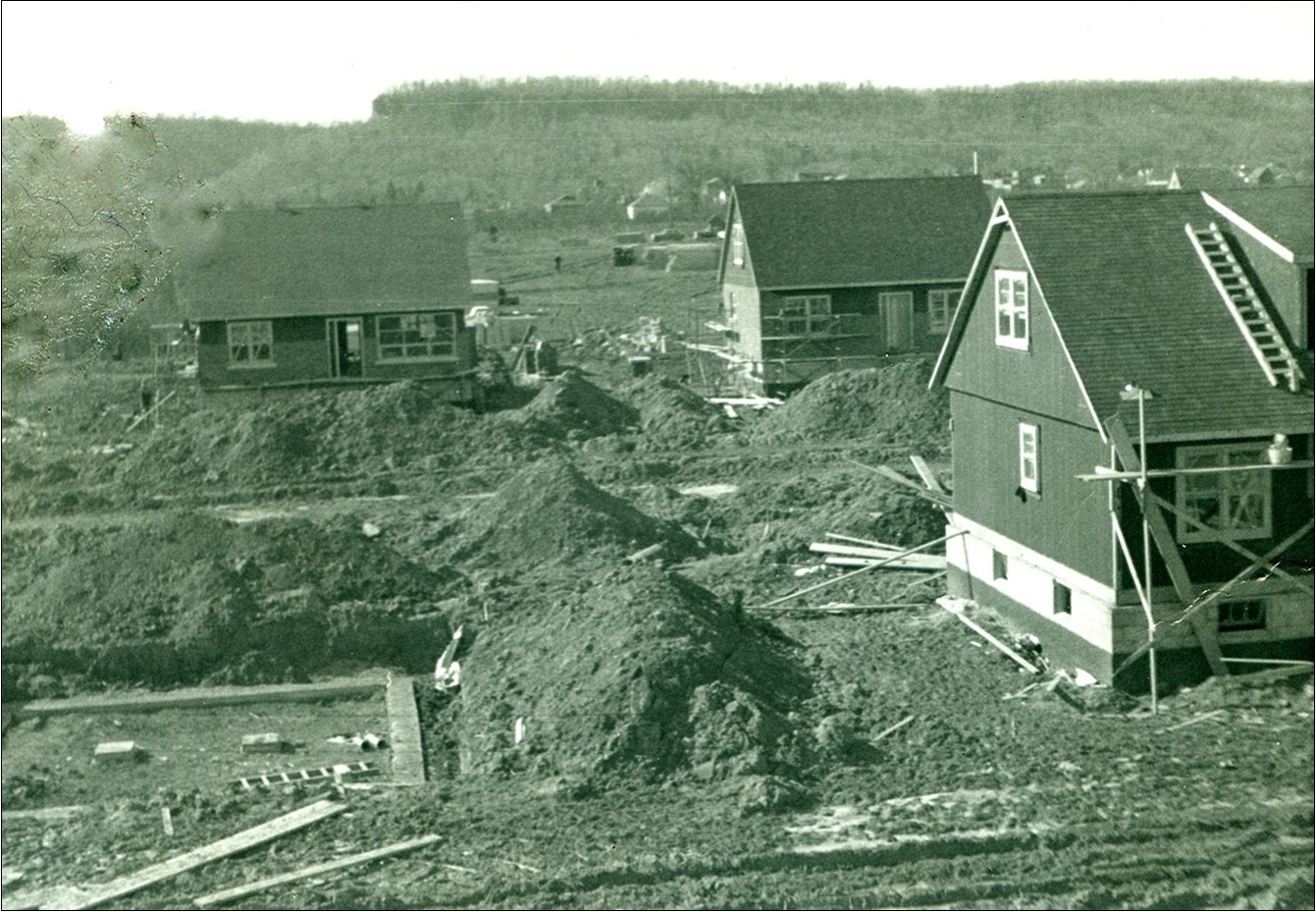 Photo noir et blanc de maisons en construction ; avec des tas de terre aux alentours.