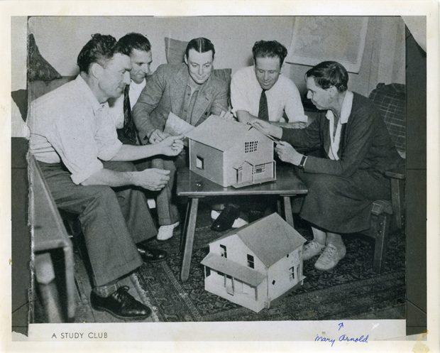 Photo noir et blanc d’un groupe d’hommes et de femmes d’un groupe d’études avec des maisons-témoins ; manuscrit, au bas : Mary Arnold.