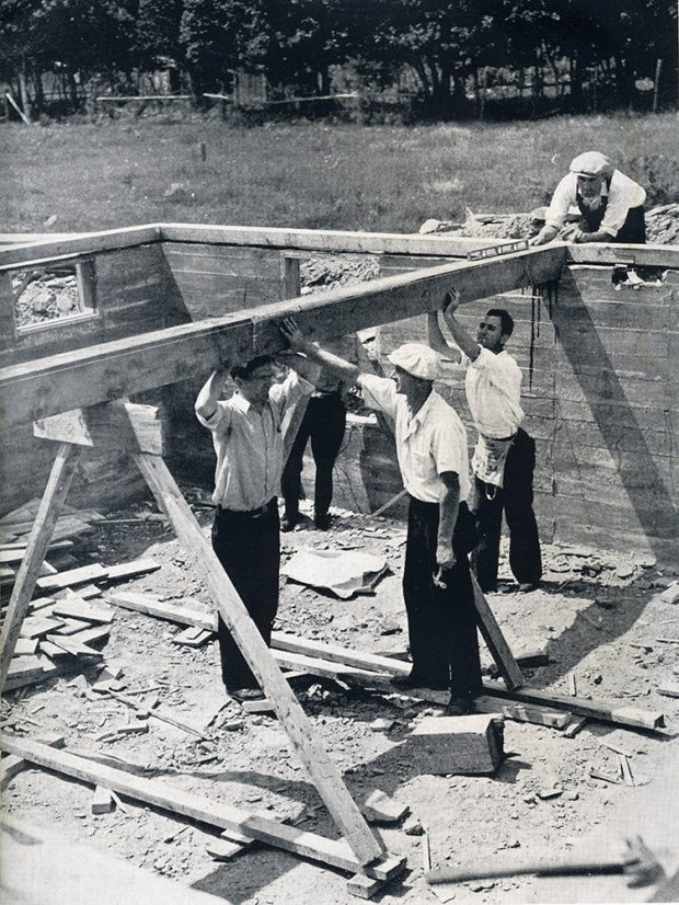 Photo noir et blanc de cinq hommes bâtissant les fondations d’une maison.