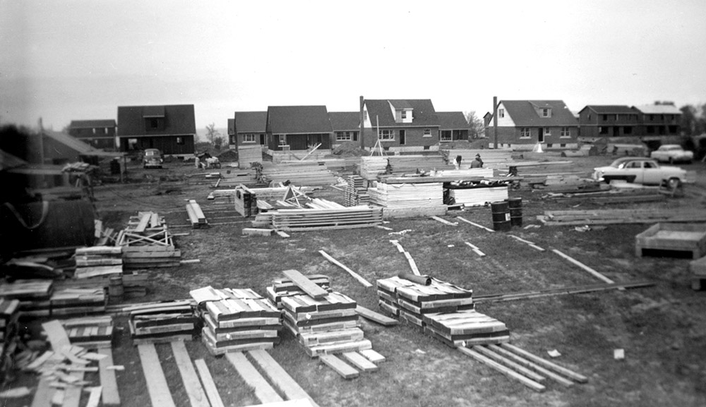 Photo noir et blanc d’un chantier de construction ; avec des tas de matériaux tout autour.
