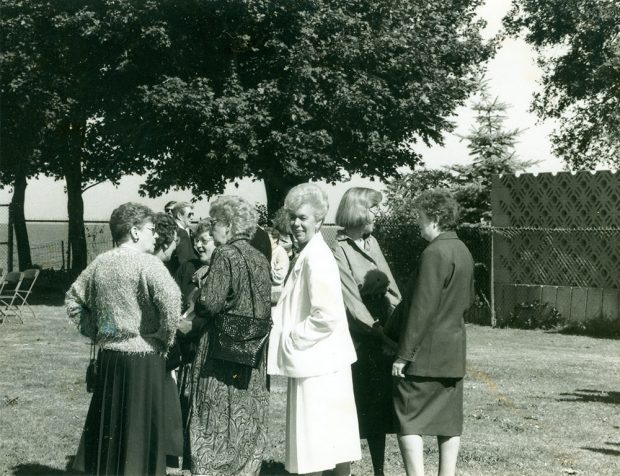 Photo noir et blanc d’un groupe de femmes discutant à l’extérieur.