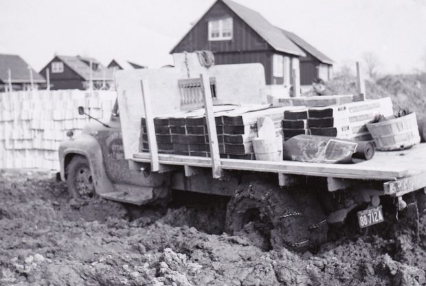 Photo noir et blanc d’un camion chargé avec des chaînes et embourbé.