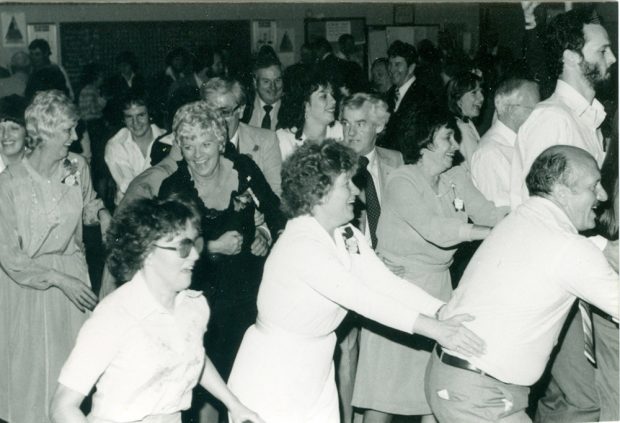 Photo noir et blanc d’un groupe d’hommes et de femmes dansant et célébrant.