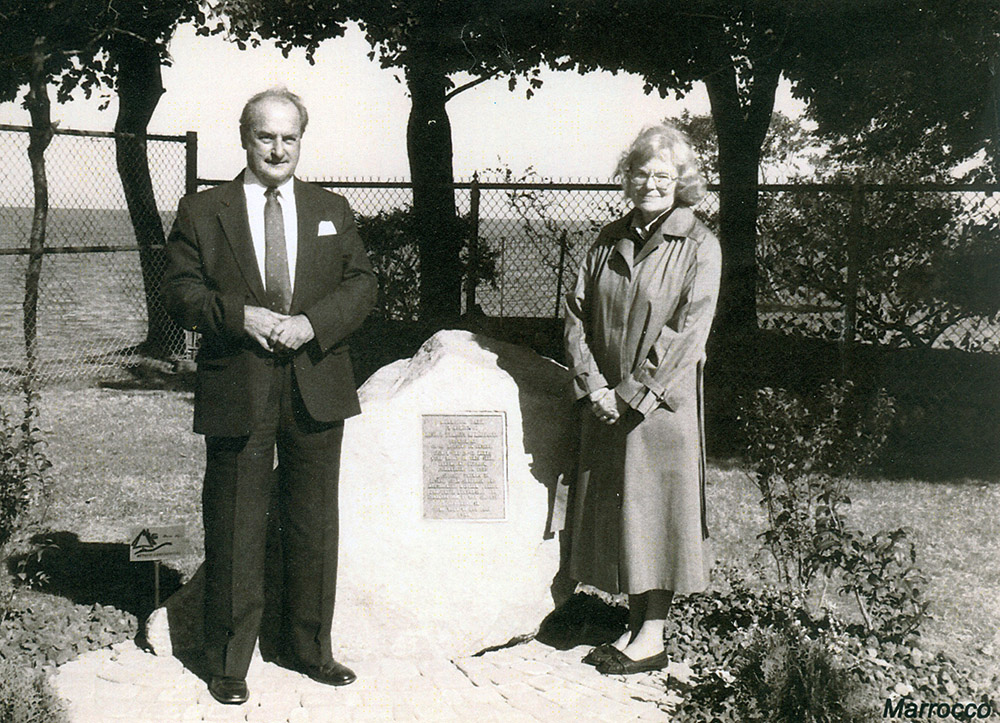 Photo noir et blanc d’un homme et d’une femme près d’une pierre sur laquelle est fixée une plaque.