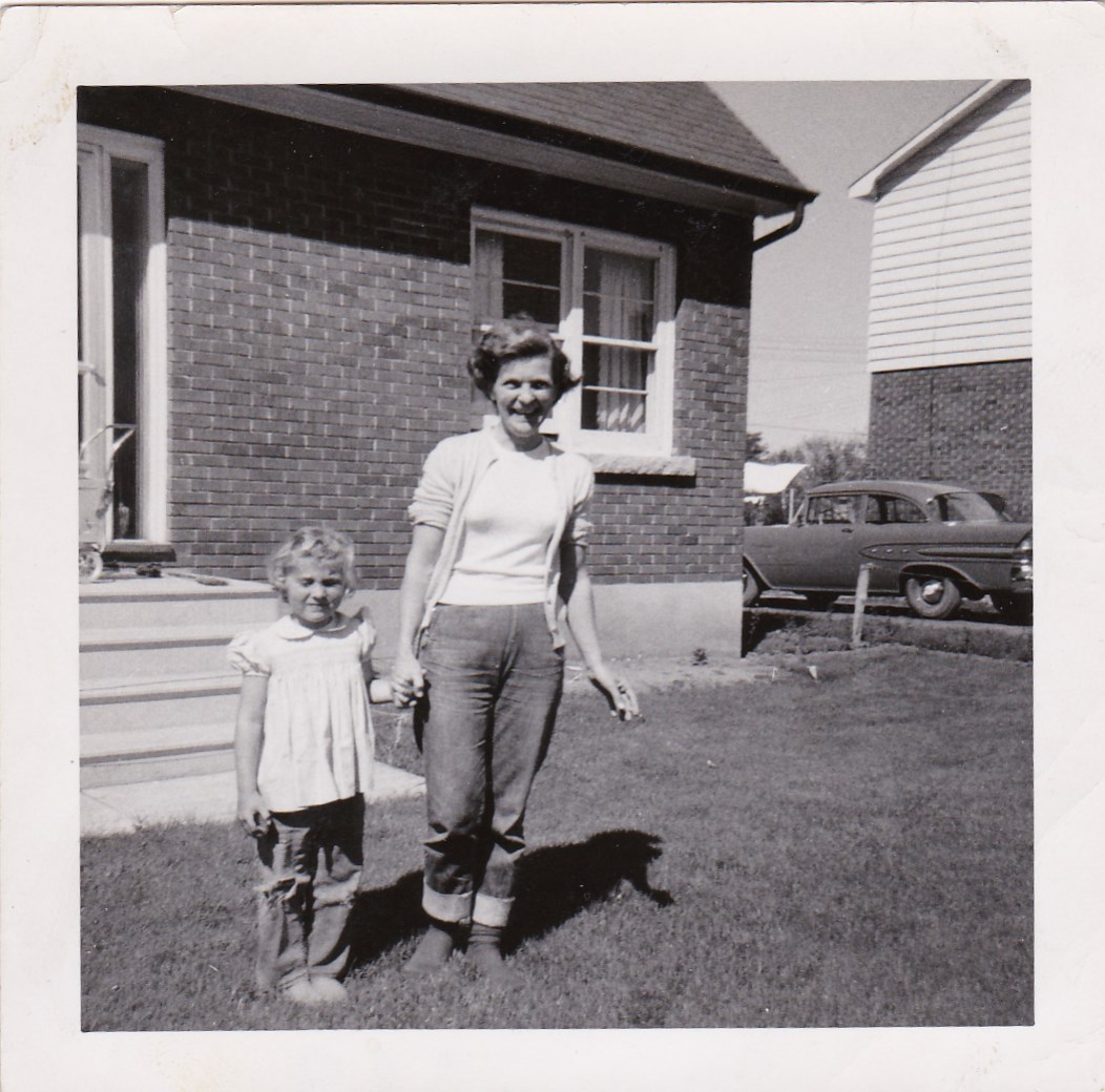 Photo noir et blanc d’une femme et d’un enfant devant une maison.