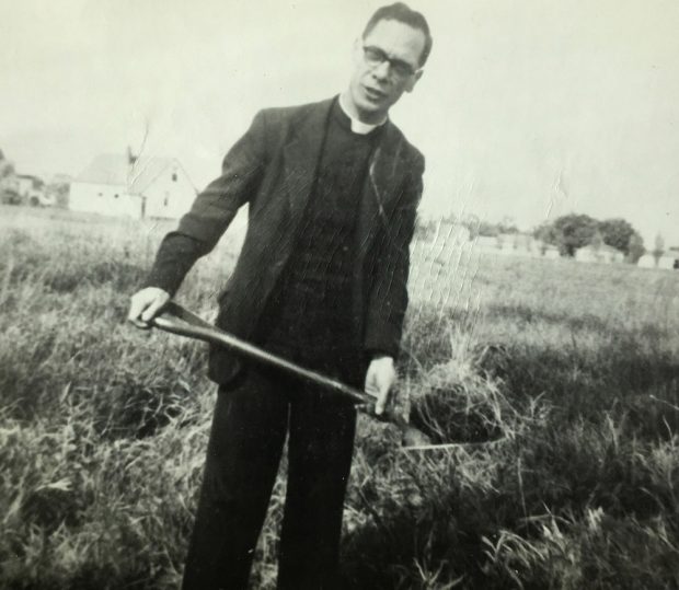 Photo d’un prêtre avec une pelle, creusant dans un champ.