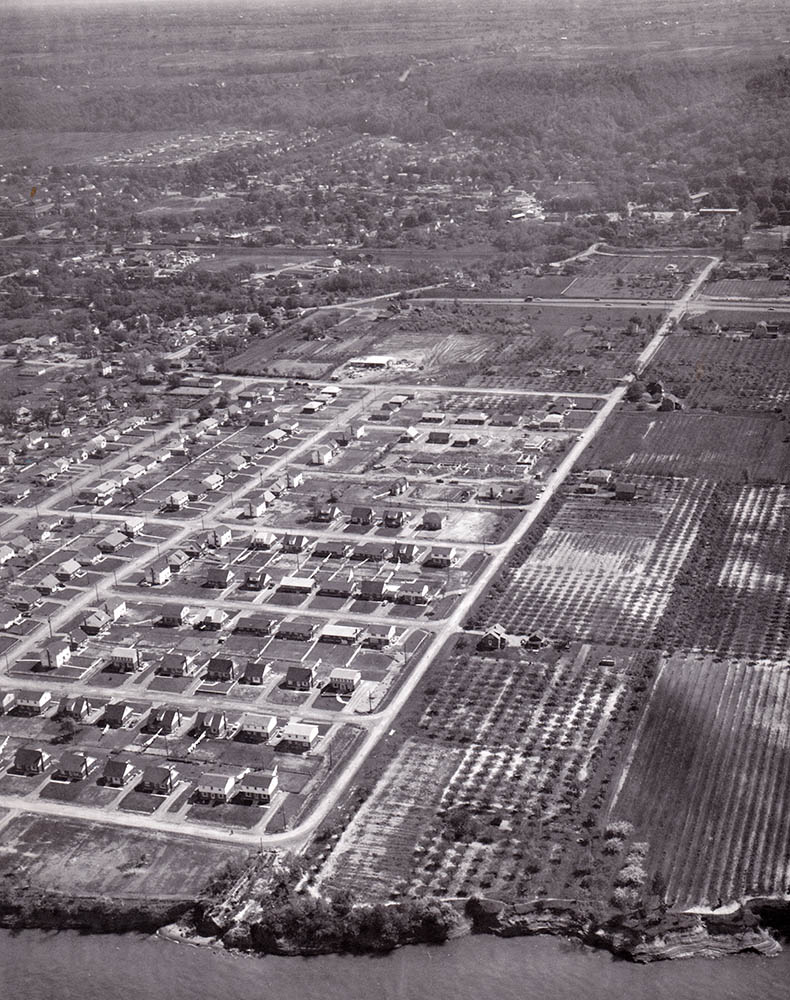 Photo noir et blanc d’une vue aérienne de Grimsby montrant les rangées de maisons individuelles sur de grands terrains, près du lac.