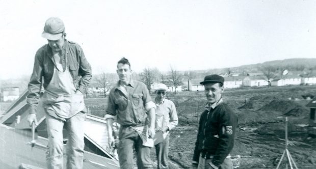 Photo noir et blanc d’un groupe de quatre hommes sur un toit.