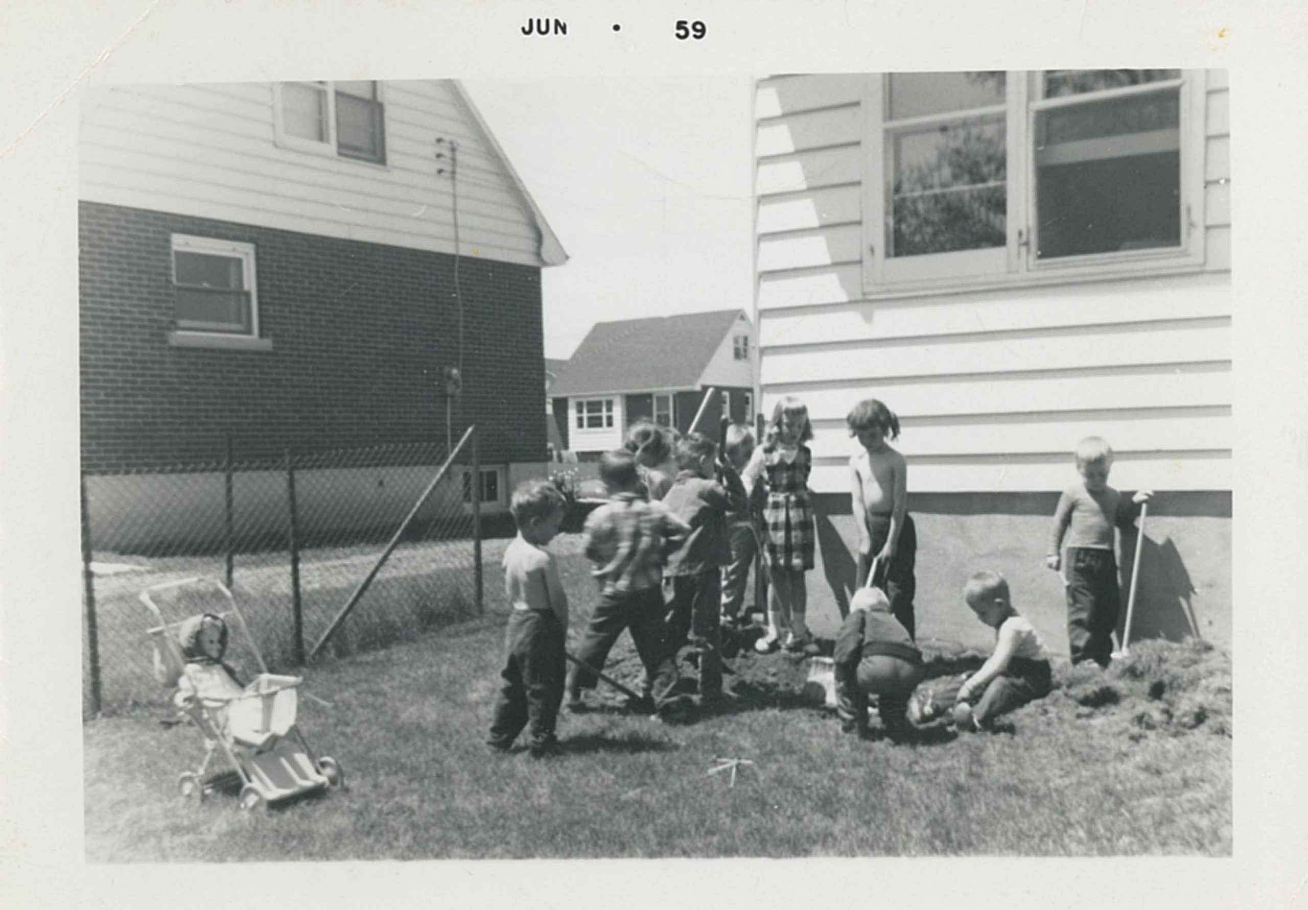 Photo noir et blanc d’un groupe d’enfants dans une cour arrière ; en haut de la photo, tapé à la machine : JUN 59.