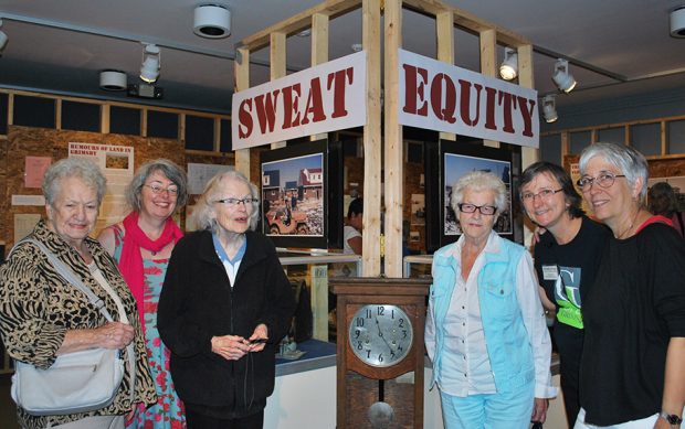 Photo couleur d’un groupe de femmes près de la pancarte Sweat Equity (À la sueur de leur front).