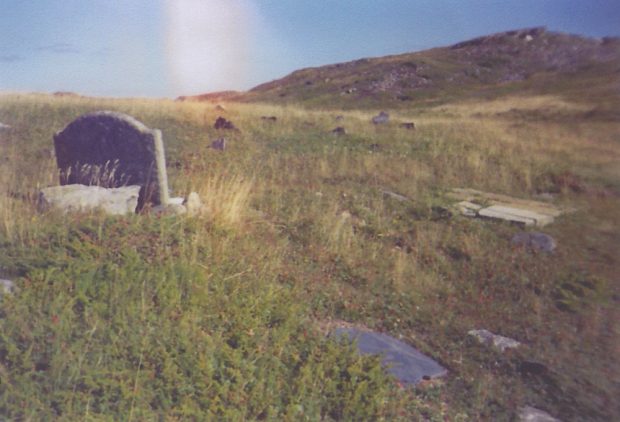 Photographie couleur d’un cimetière sur une colline herbeuse.