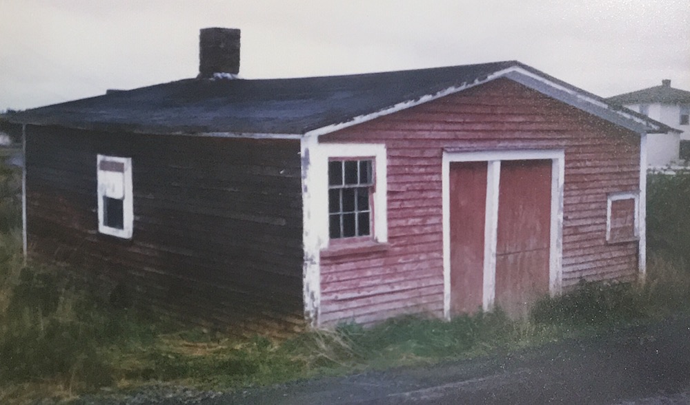 Photographie en couleur de l’extérieur de la forge Littlejohn, un bâtiment d’un étage peint en rouge avec des boiseries blanches qui paraît usé par les éléments.