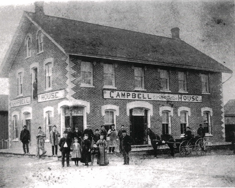 Photo en noir et blanc d’un immeuble de briques, avec des gens sur la rue à l’avant-plan