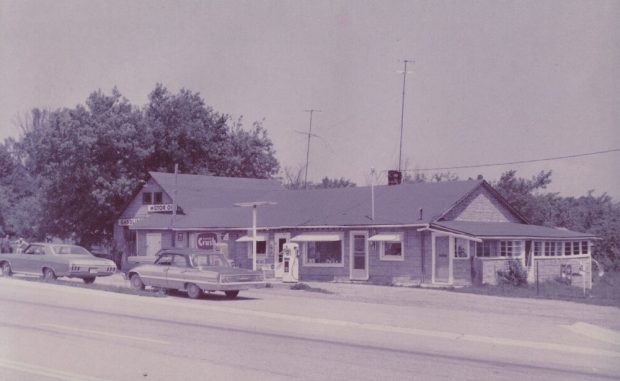 Photo couleur d’un bâtiment avec voitures et pompes à essence à l’avant-plan