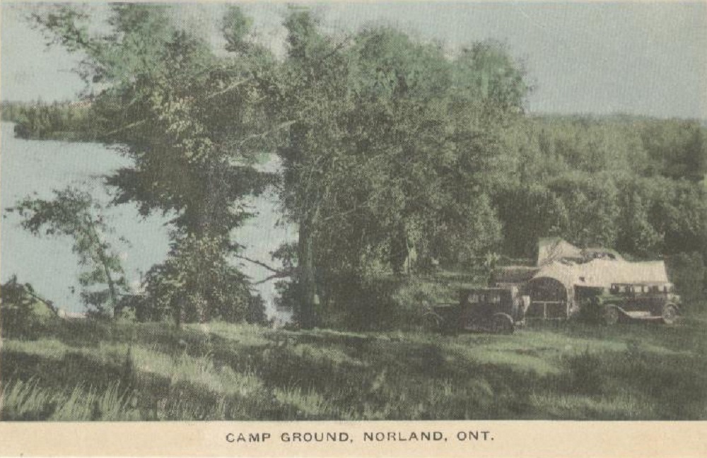 Photo couleur de véhicules anciens avec des tentes blanches sous des arbres et le lac à l'arrière-plan