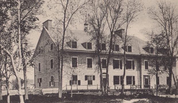 Photographie noir et blanc du couvent de Sainte-Anne à trois étages avec fenêtres munies de volets et toit à deux versants avec petit clocher au centre et six lucarnes.