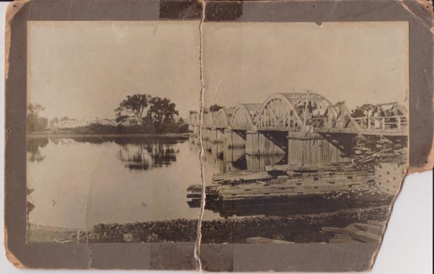 Photographie en noir et blanc du pont de Sainte-Anne dont deux arches de la structure en bois ont été détruites par un éboulis avec les débris gisant dans la rivière.
