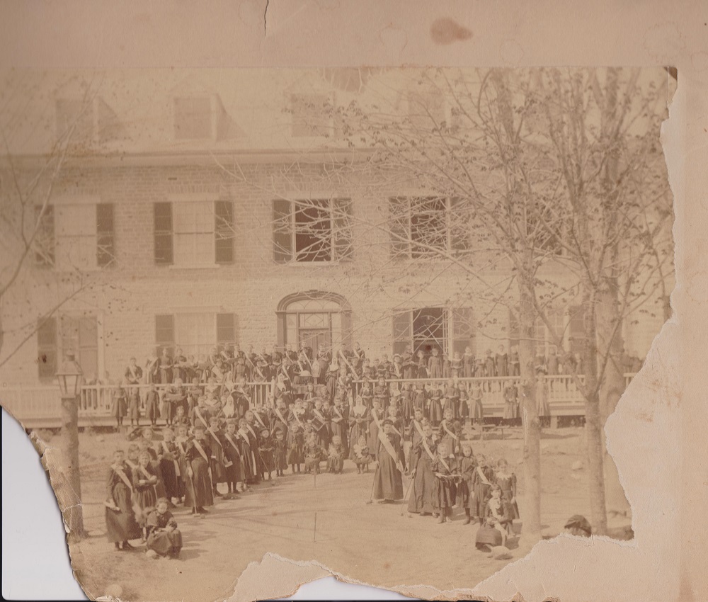 Morceau de photographie d’archives d'élèves et d'enseignantes devant le couvent de Sainte-Anne.