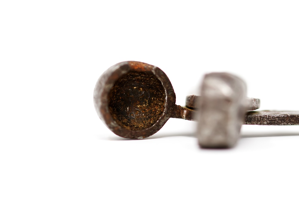 Photographie de l'extrémité creuse d’un moule à balle ronde en fer et métal.