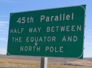 Photo d'un panneau routier sur lequel est inscrit : 45e parallèle, à mi-chemin entre l'équateur et le pôle Nord.