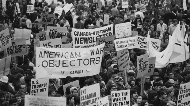 Groupe de manifestants contre la guerre au Vietnama; sur les pancartes, on peut lire : End the War in Vietnam, End Canadian Complicity, American War Objectors. 