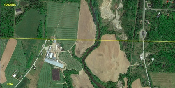 Vue aérienne de la ferme Hurtubise montrant que le 45e parallèle coupe en deux la ferme et la maison.