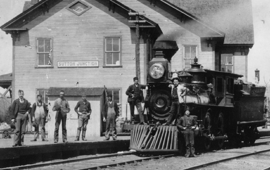 Une locomotive arrive en gare de Sutton Junction attendue sur le quai par une équipe de cheminots .