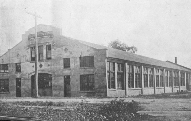 Photo noir et blanc qui présente un bâtiment monumental en brique sur la rue Cutting à Coaticook. Sur le Fronton de l’édifice, il est inscrit « A.O.Norton LTD ».