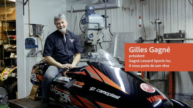 Photo couleur présentant l’inventeur Gilles Gagné assis sur un véhicule dans un atelier. On y voit des appareils, des outils ainsi que des engins.