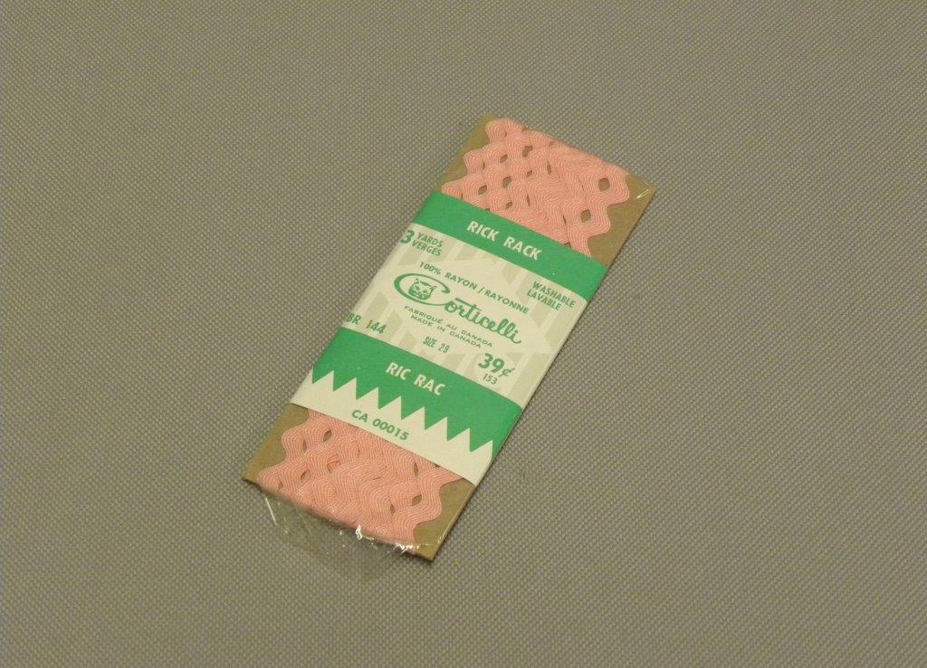 Photo couleur d’un paquet de rubans roses dans un emballage avec une grosse étiquette blanc-gris et vert qui donne les propriétés du produit.