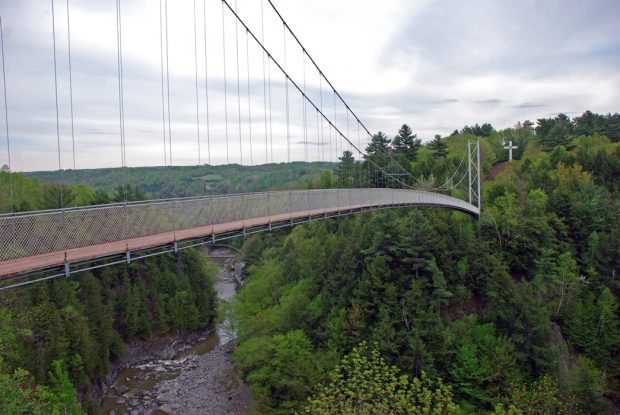 Photo couleur qui montre le Pont suspendu dans un écrin de verdure et la gorge de Coaticook en contrebas.