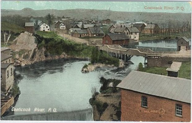 Photo couleur présentant une vue aérienne de la rivière Coaticook. On y voit un pont et des maisons.